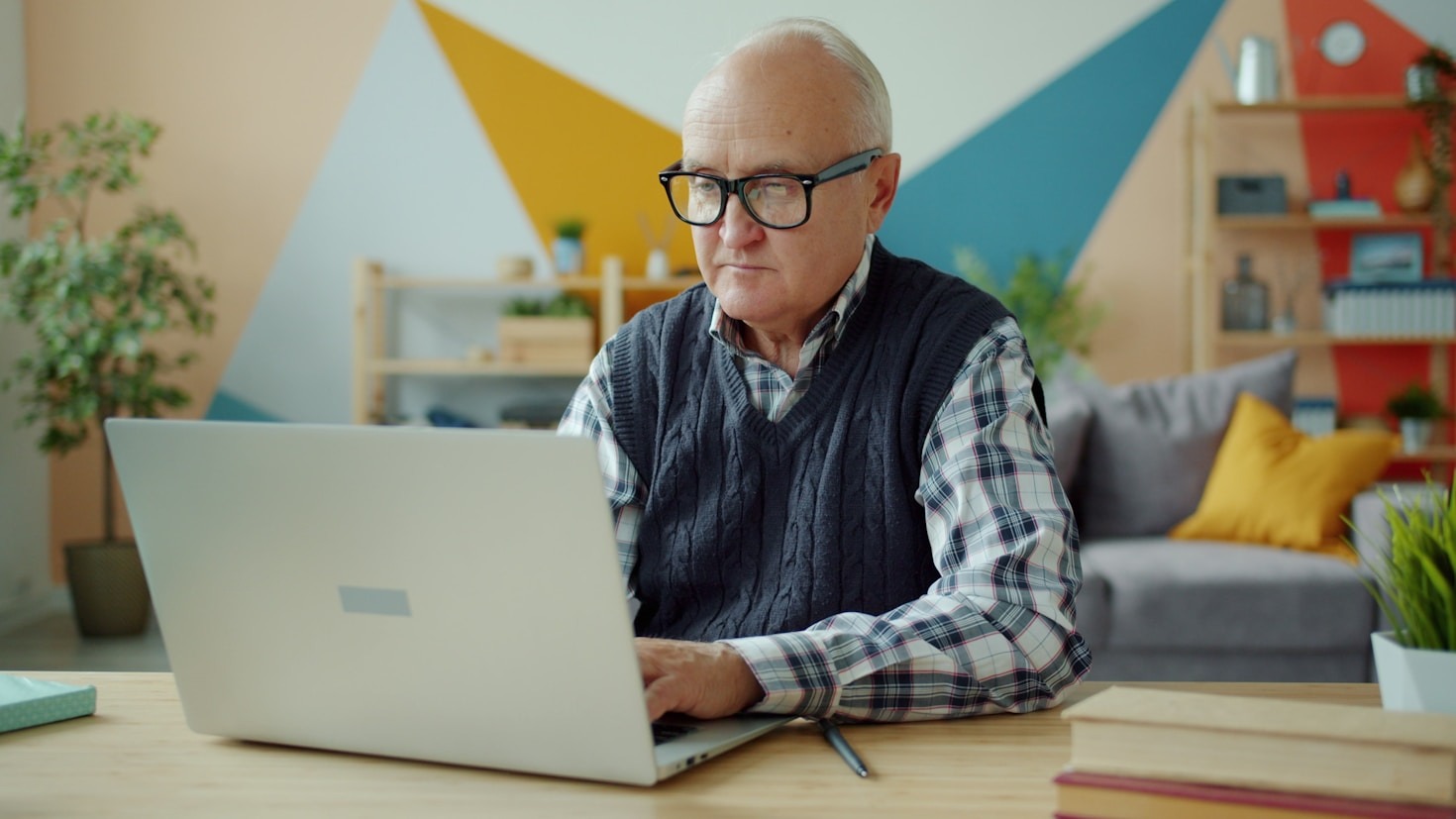Man wearing glasses at a desk working on a laptop