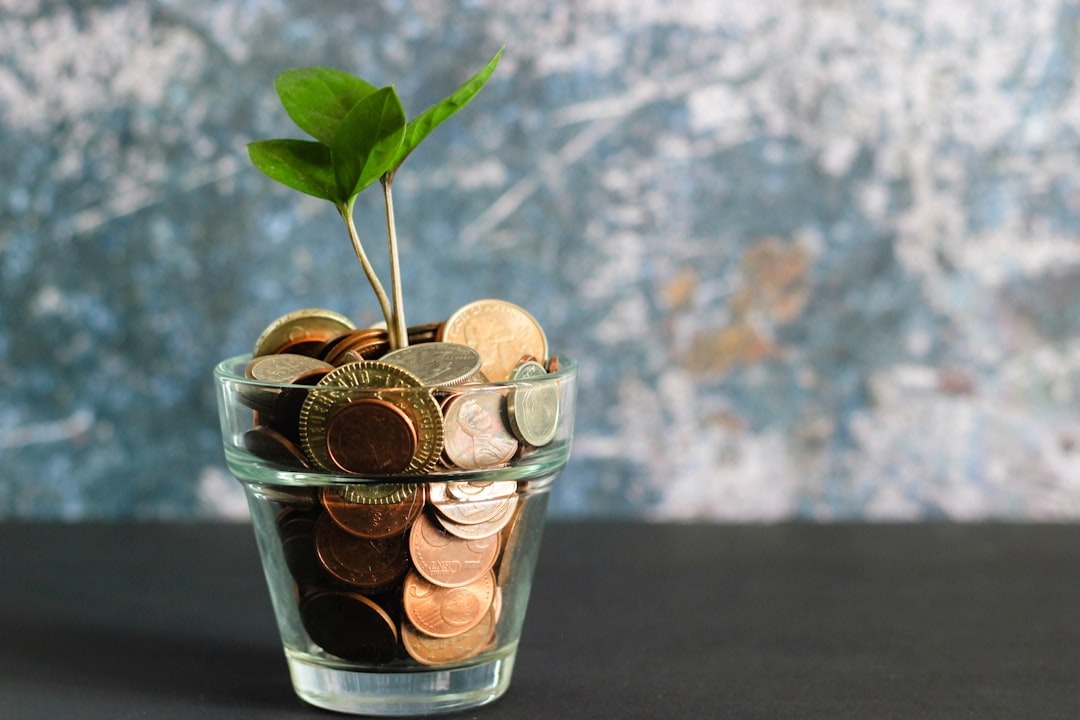 A glass full of pennies with seedling growing from within