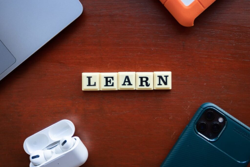 Learn spelled out in scrabble tiles on table top with periphery items visible around corner of the picture